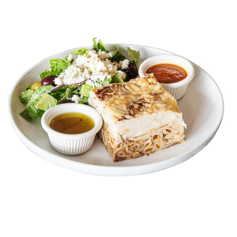 Pastitsio with a side salad topped with feta cheese, olives, and two dipping sauces.