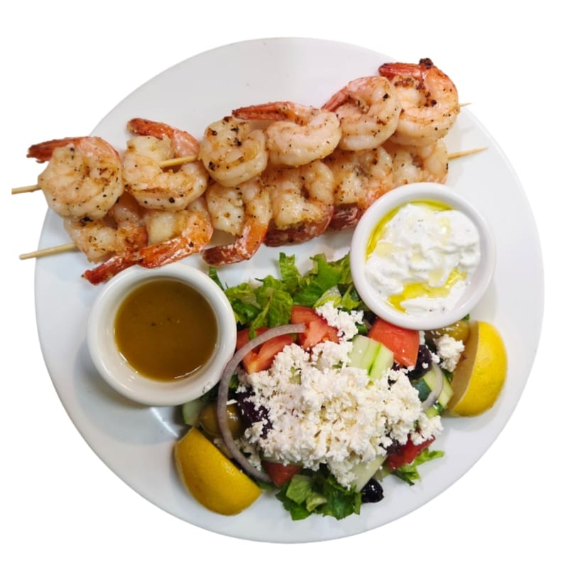Grilled shrimp skewers with a Mediterranean salad, feta cheese, and two dipping sauces.